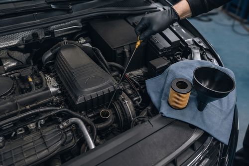 Odprt motorni prostor med rednim servisom, merilna palica za olje in nov oljni filter na čisti krpi